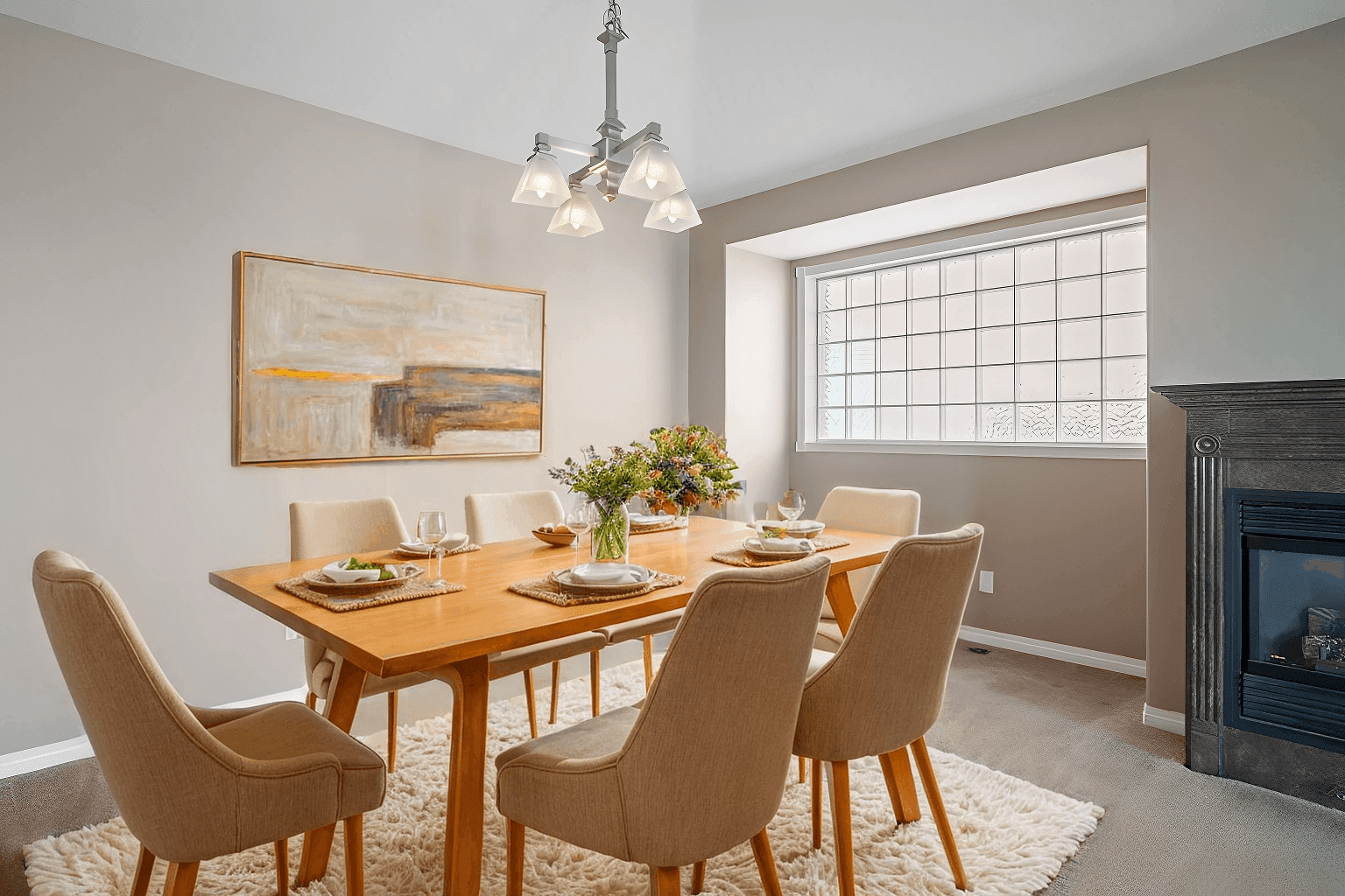 Our story 2 A modern dining room with a wooden table and six beige chairs on a white rug. A decorative centerpiece and elegant place settings create a cozy, inviting atmosphere.
