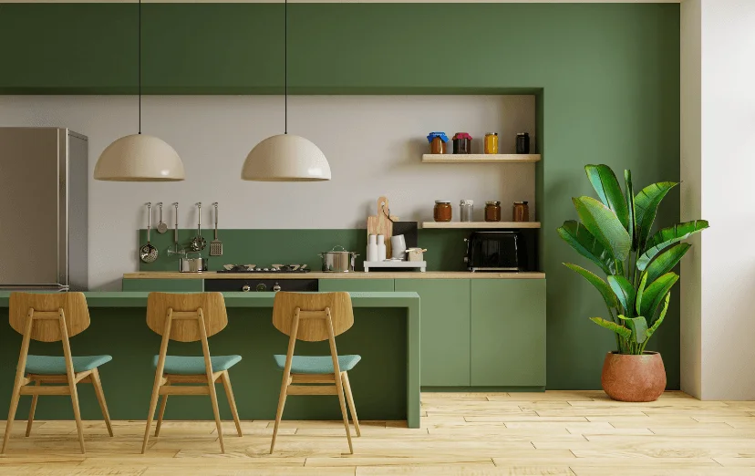 Modern kitchen with green cabinets and wall, light wood floor, and three wooden bar stools. Cream pendant lights and a potted plant enhance the serene vibe.