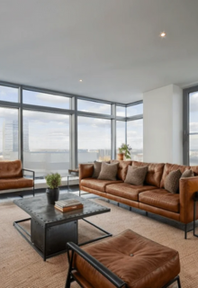 Home 5 Luxurious living room with large windows offering a city view. Features brown leather sofas, a black metal coffee table, and neutral decor creating a stylish, modern ambiance.